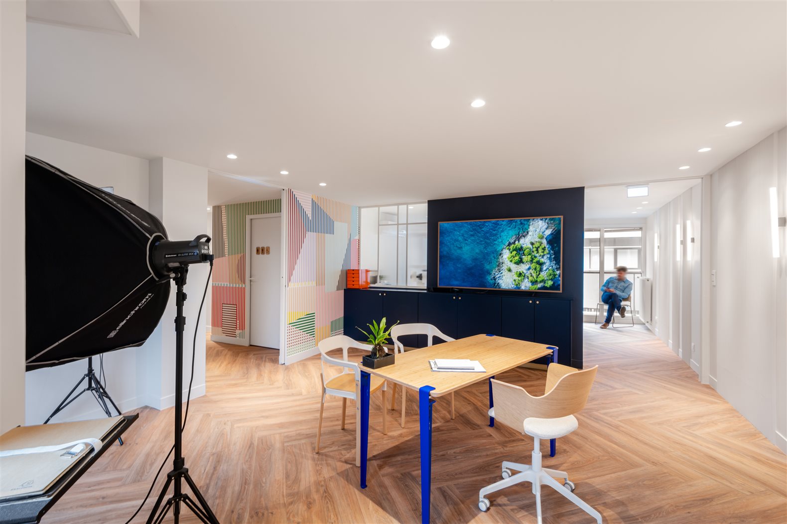 Espace de consultation avec table en bois et écran mural, boîte à lumière de studio photo au premier plan