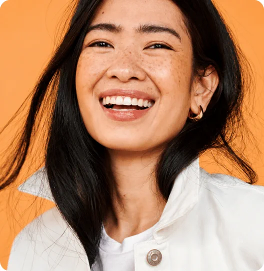 Femme souriante aux cheveux noirs sur fond orange